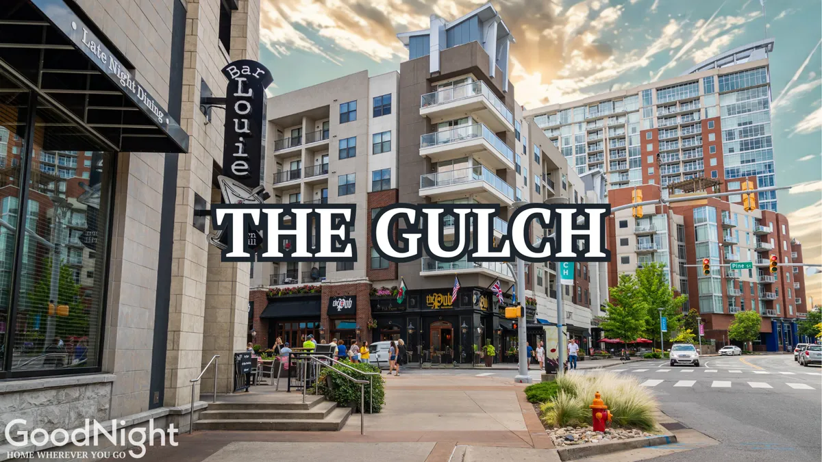 An exterior street view in The Gulch, showcasing the Bar Louie sign, surrounding modern buildings, pedestrians, and active street life. People are seen dining at outdoor cafes and socializing in a vibrant urban setting.
