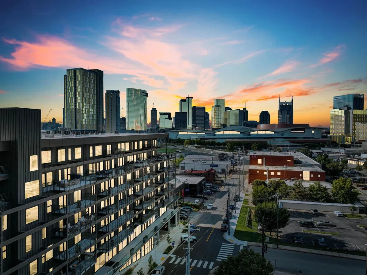 A striking image of a modern building set against the Nashville city skyline at sunset, with vibrant colors and a bustling urban vibe, emphasizing downtown’s energy and accessibility to dining and networking venues.